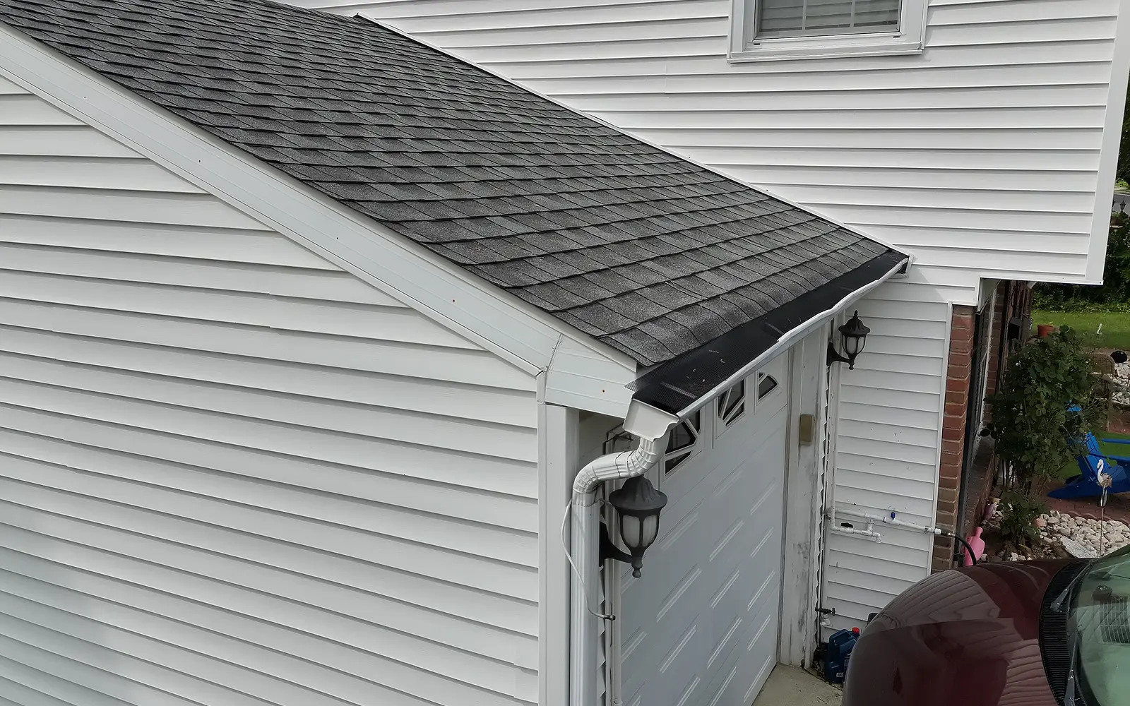 Drone view of a garage roof, gutter, and downspout.